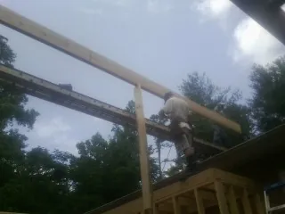 Carpenter setting a ridge beam over a new addition frame — Ice Dam Removal by Roofing Brothers in Barry