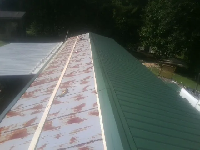 Old rusted panels beside newly installed green metal roofing — Wind Damage Roof Repair by Roofing Brothers in Barry
