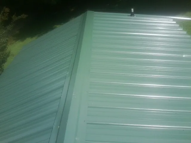 New green metal panels meeting at the ridge of a roof — Flat Roof Repair work by our crew in Barry
