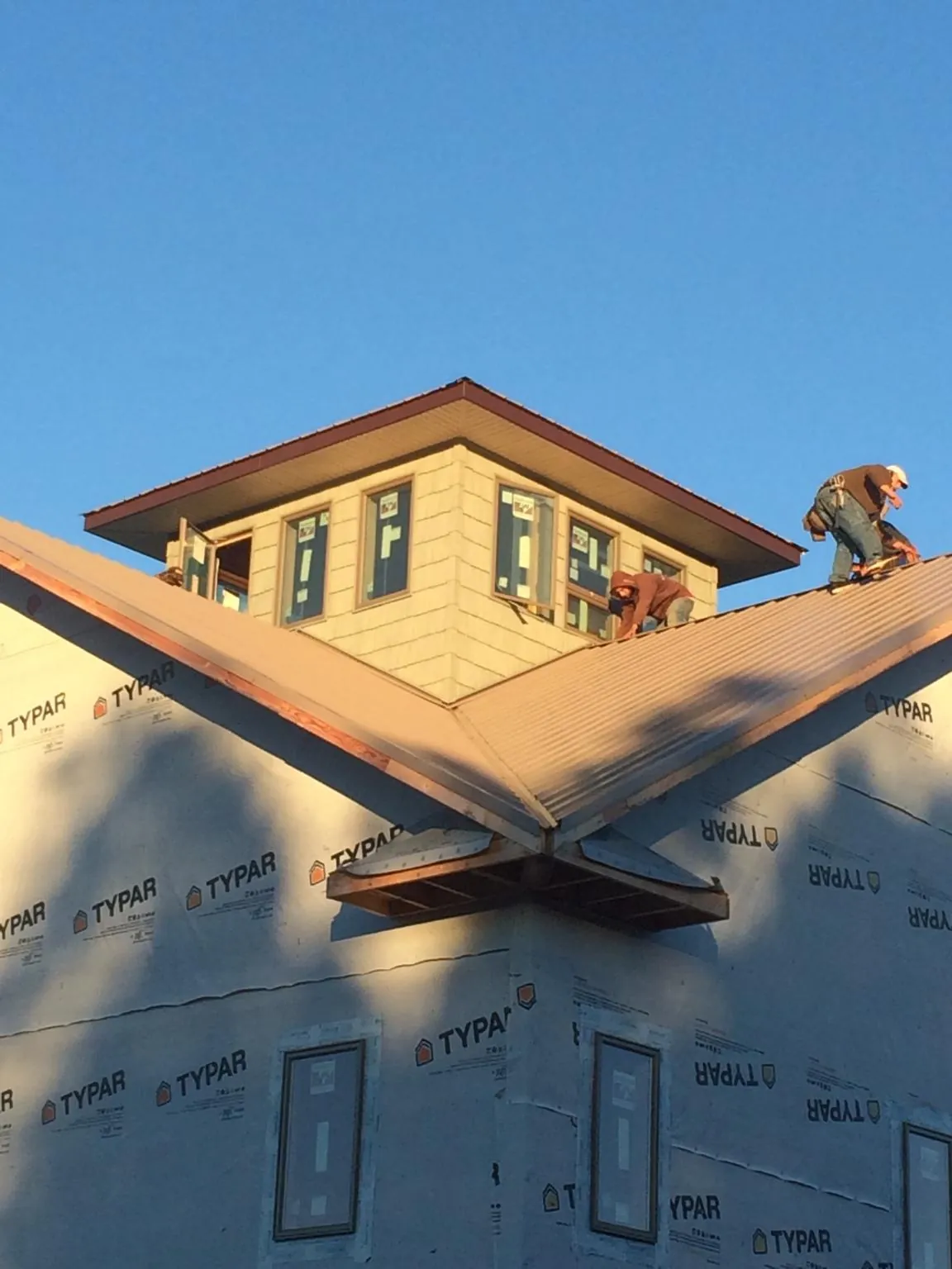 Roofers working around a rooftop cupola on a new metal roof at sunset — Roof Waterproofing in Barry by Roofing Brothers
